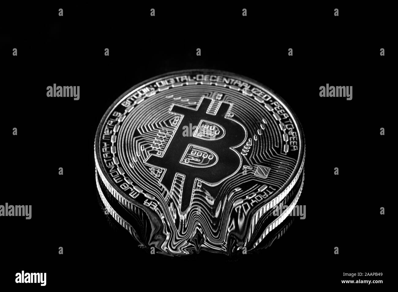 Bianco e nero Bitcoin fisico crypto moneta giù di fusione sotto una luce brillante con sfondo nero (F2) Foto Stock
