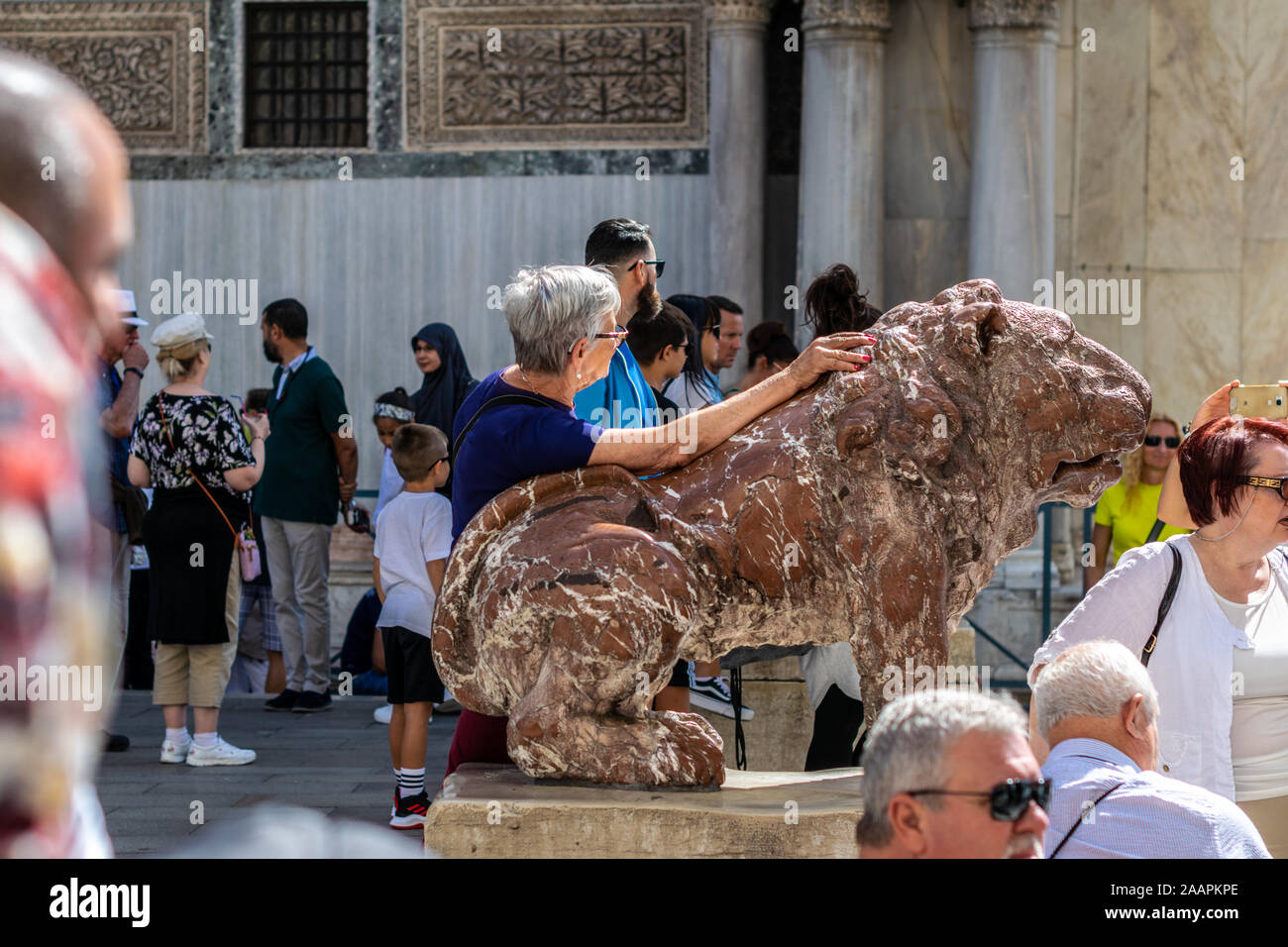 I turisti in posa con uno del rosso leoni di marmo nella Piazzetta dei Leoncini, da Piazza San Marco, Venezia, Italia Foto Stock