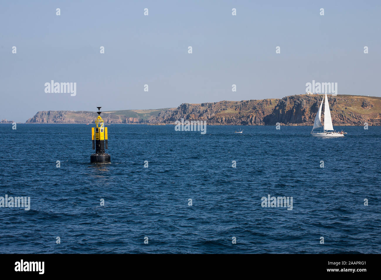 Yacht a vela in un mare calmo passato la boa Runnelstone off Gwennap testa: Land's End oltre, Cornwall, Regno Unito Foto Stock