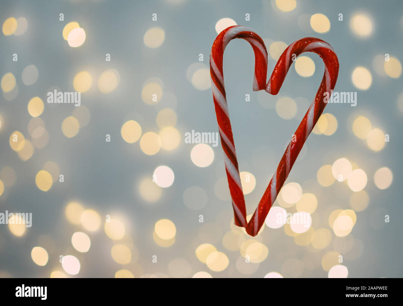 Un candy cane cuore appeso davanti a una luce di Natale sfondo Foto Stock