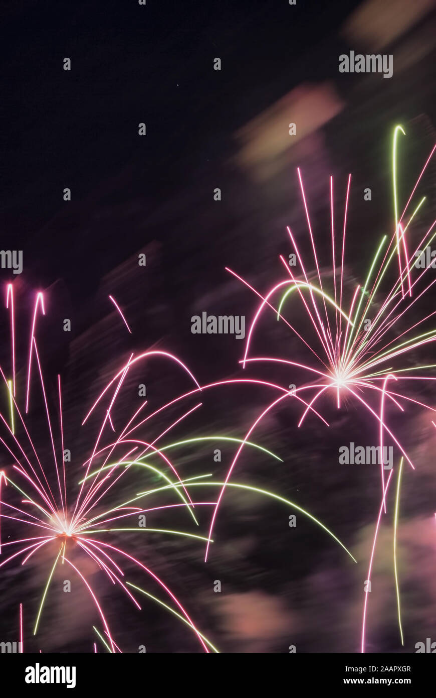 Una rosa e verde fuochi d'artificio girato durante una vacanza celebrazione. Copia di spazio nella parte superiore a sinistra e l'area centrale del cielo. Foto Stock