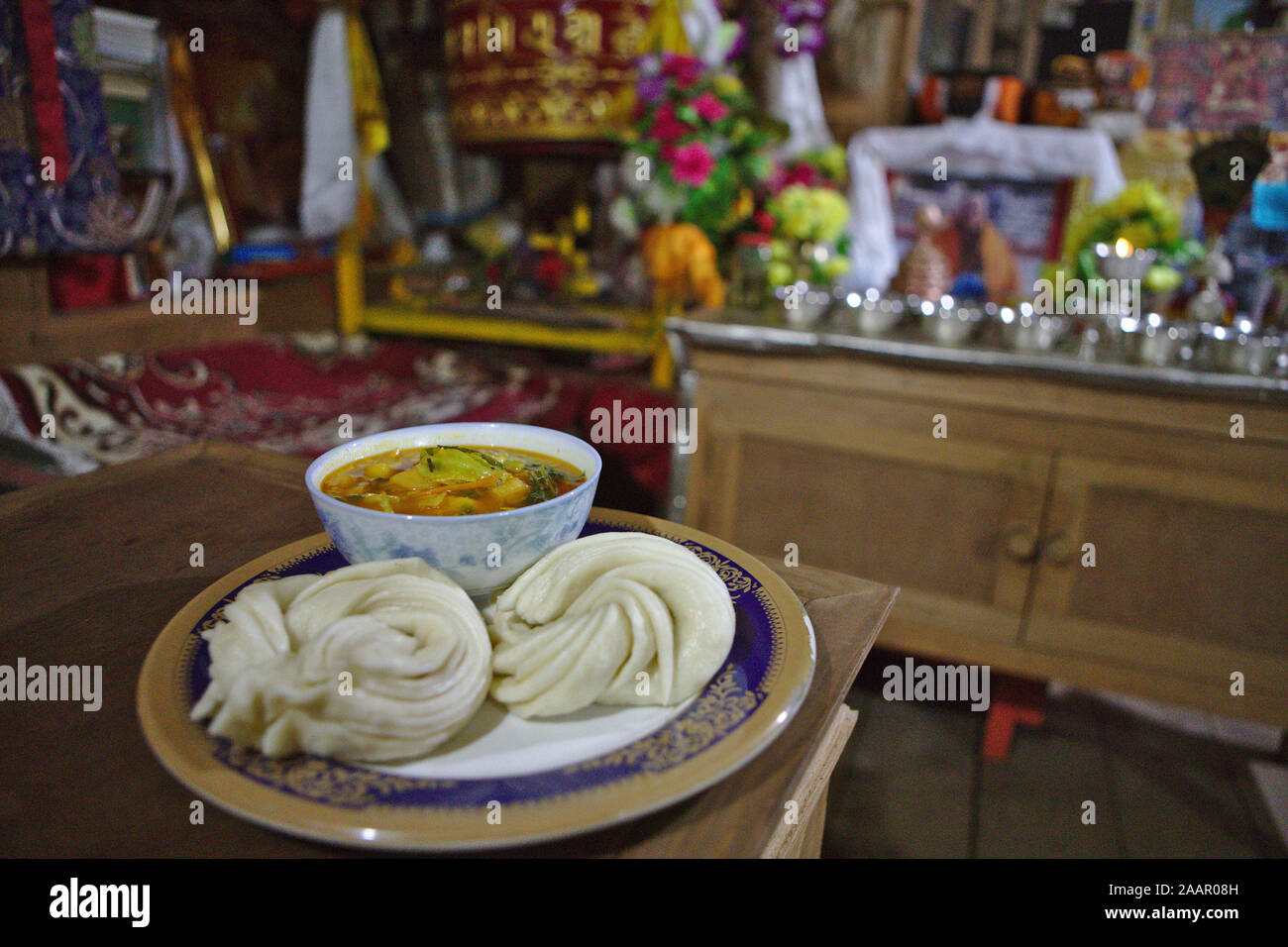 Due vaporizzato rotoli tibetano chiamato tingle con un curry vegetale su un decorativo piastra blu Foto Stock