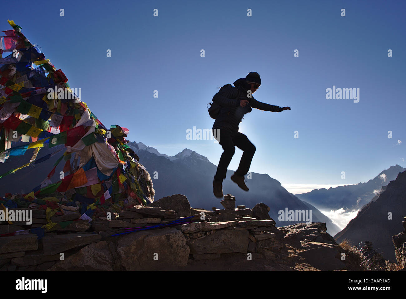 Silhouette di uomo saltare in cima Kyanjin Ri con Langtang valle in background Foto Stock