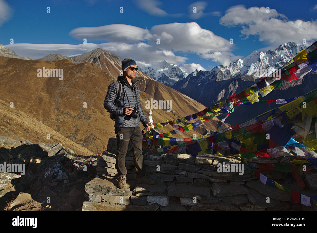 Uomo occidentale in cima Kyanjin Ri indossando down jacket e attrezzi escursionistici Foto Stock