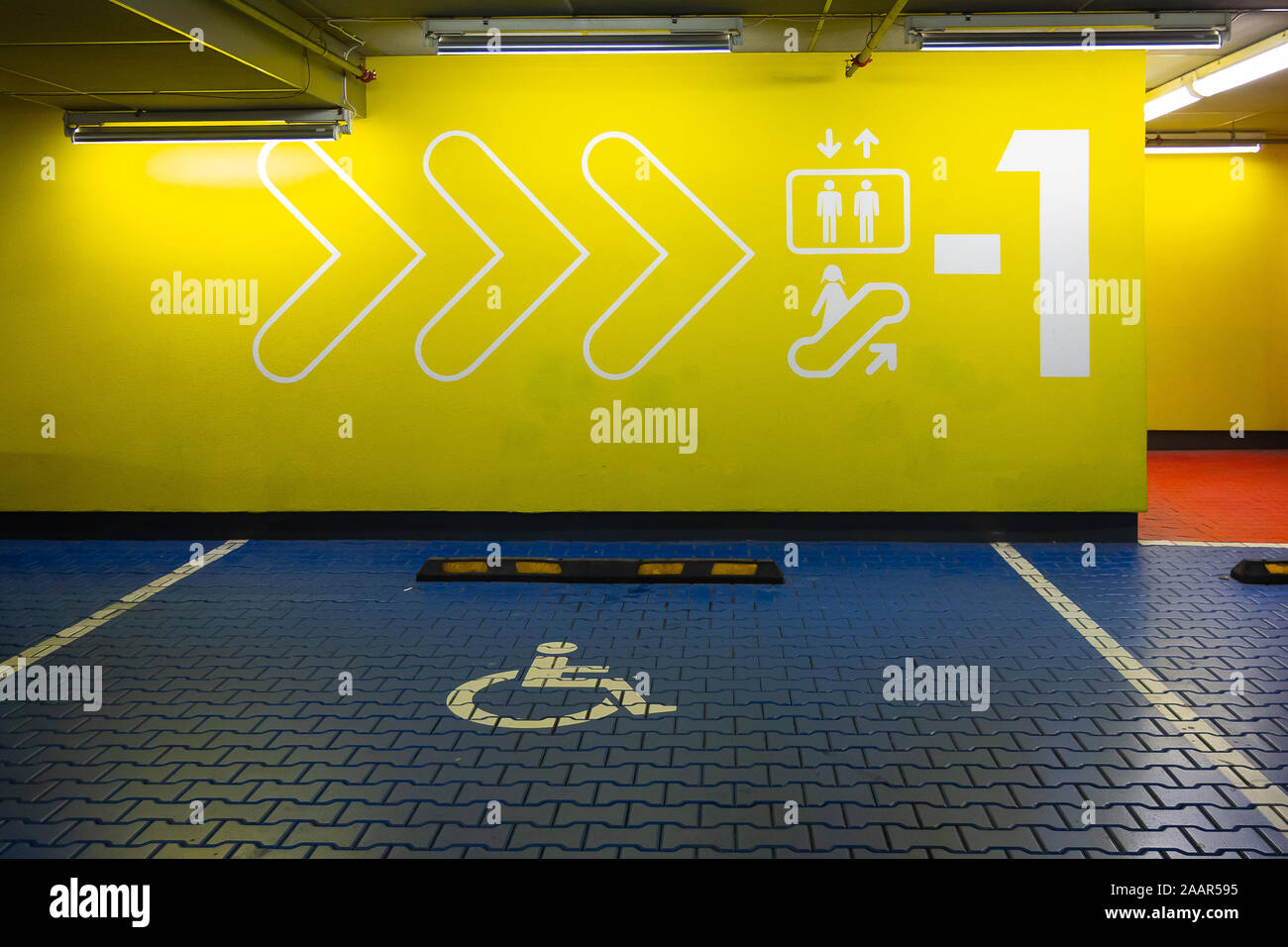 Riservati auto blu lo spazio di parcheggio per disabili. International Simbolo disabili dipinta in un centro commerciale parcheggio. Foto Stock