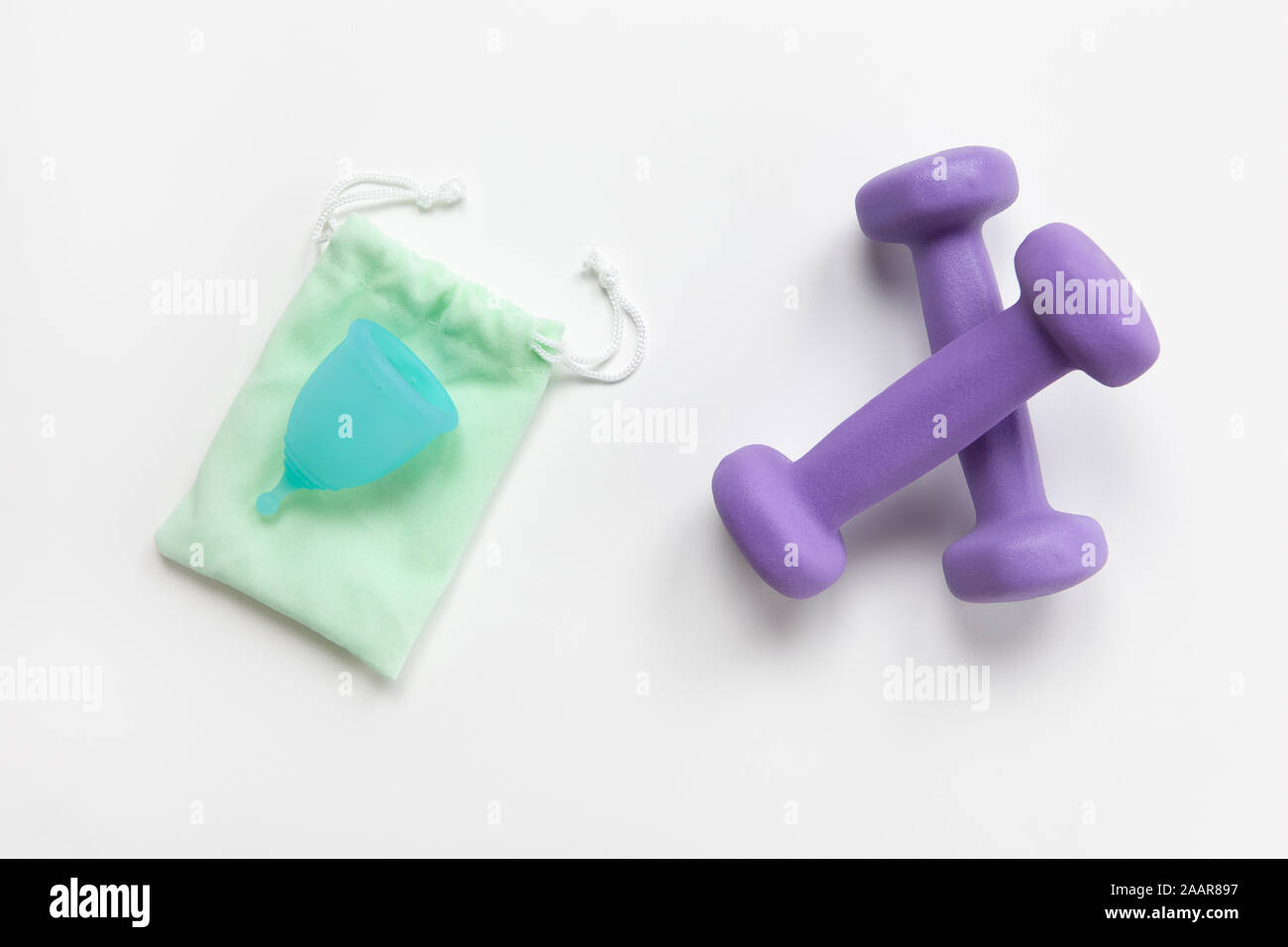 Turchese coppa mestruale su verde piccola borsa e violetta manubri su sfondo bianco. Il concetto di rifiuti zero, risparmi, minimalismo, senza limiti. Hygi femminile Foto Stock