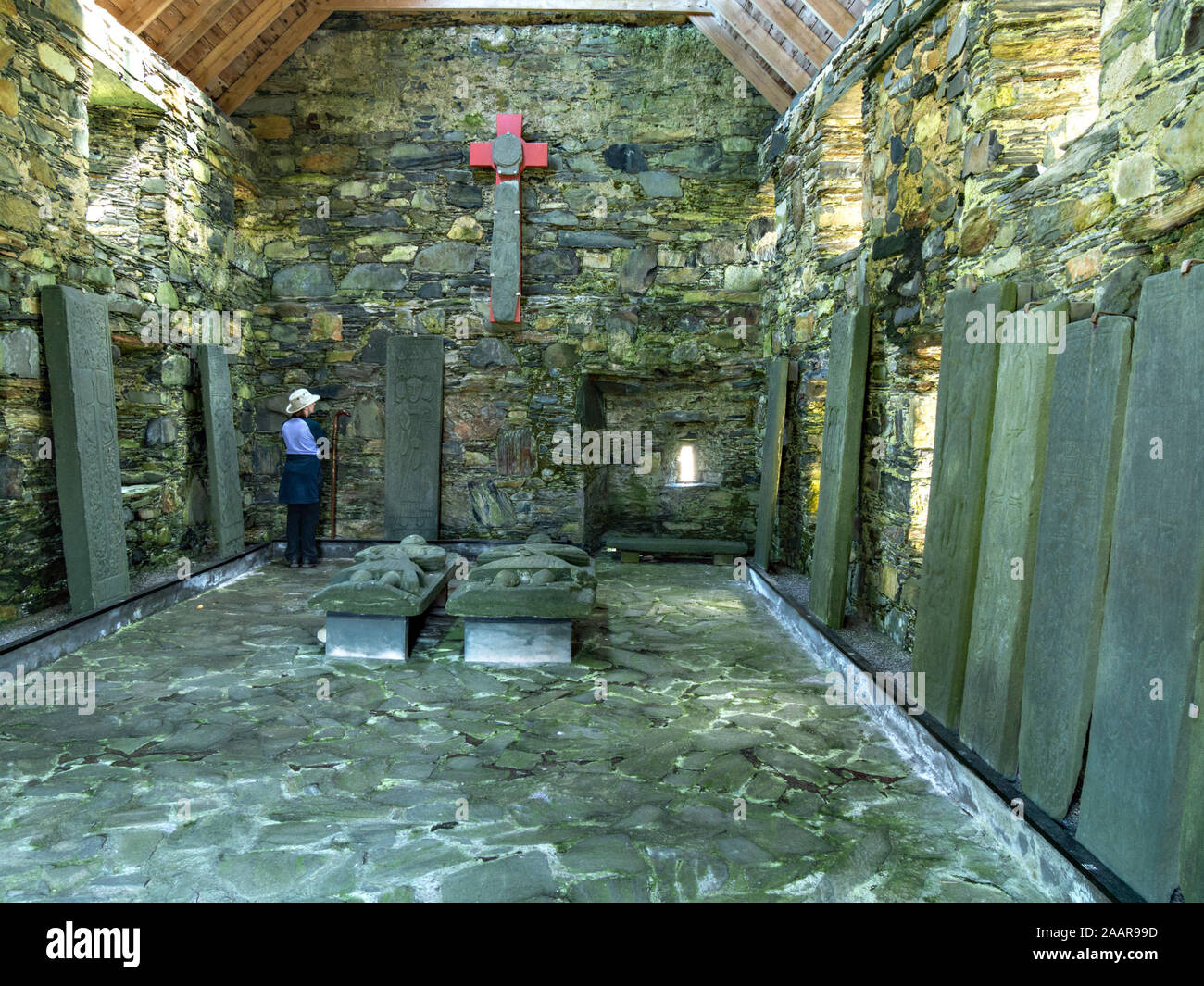 Donna che guarda uno schermo di antiche lapidi scolpite dentro la prima casa, Oronsay Priory, Isola di Oronsay, Colonsay, Scotland, Regno Unito Foto Stock