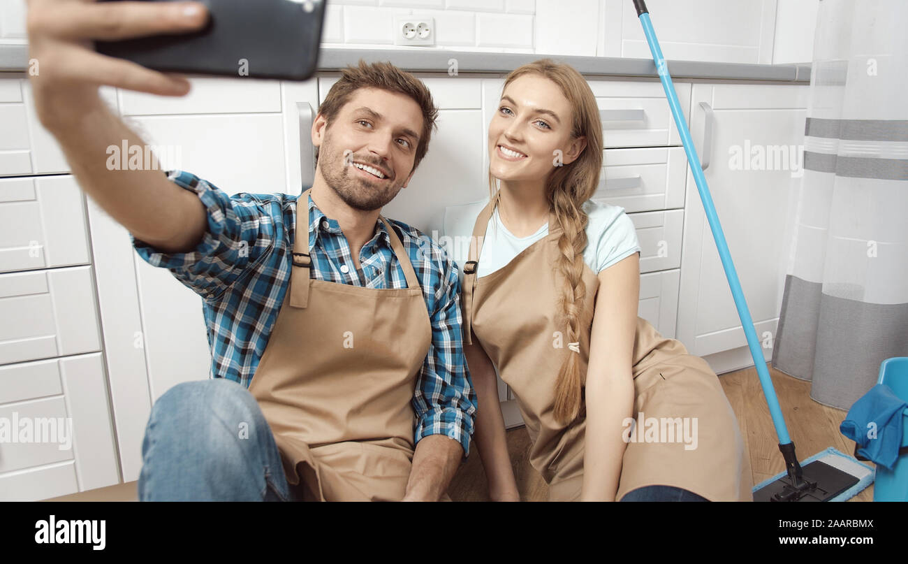 Felice coppia giovane fa un selfie dopo una dura la pulizia della cucina Foto Stock