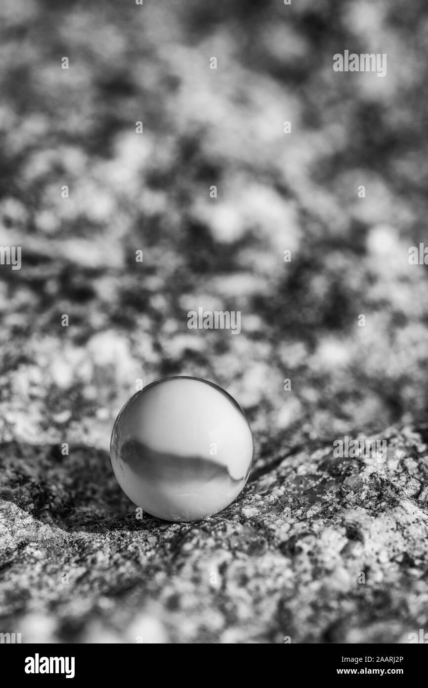 Marmo di vetro bianco e nero su superficie ruvida di granito. Metafora qualcosa perso, salute mentale, perdere i vostri marmi, sfere astratte, focalizzare la vostra mente. Foto Stock