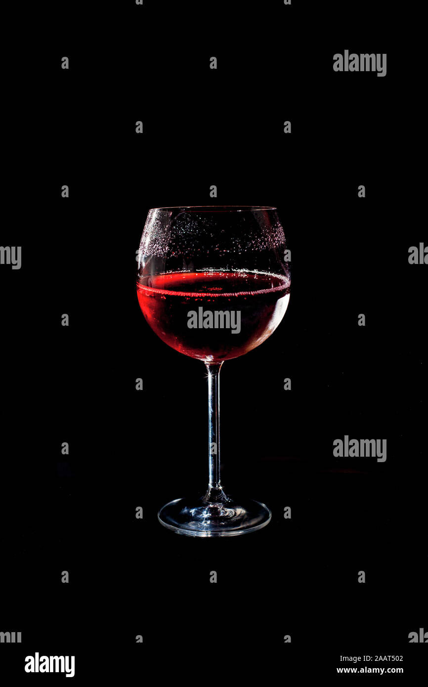 Un bicchiere di rosso bevanda fredda con sfondo nero Foto Stock