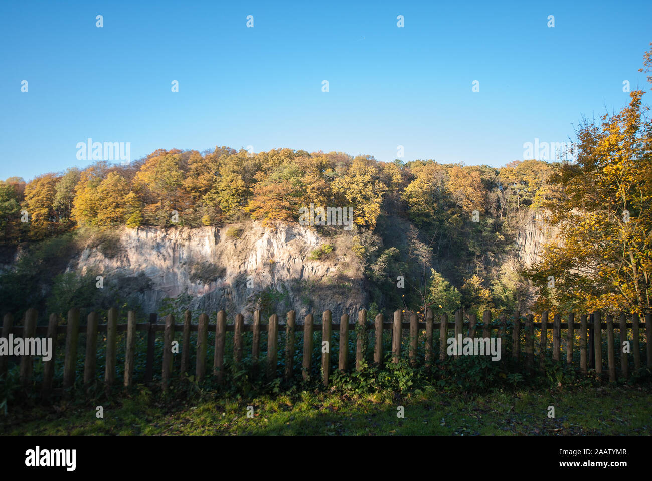 Recinto sul bordo della parete di roccia del Weilbergsee con la foresta di autunno nella luce della sera. Novembre scena. Foto Stock