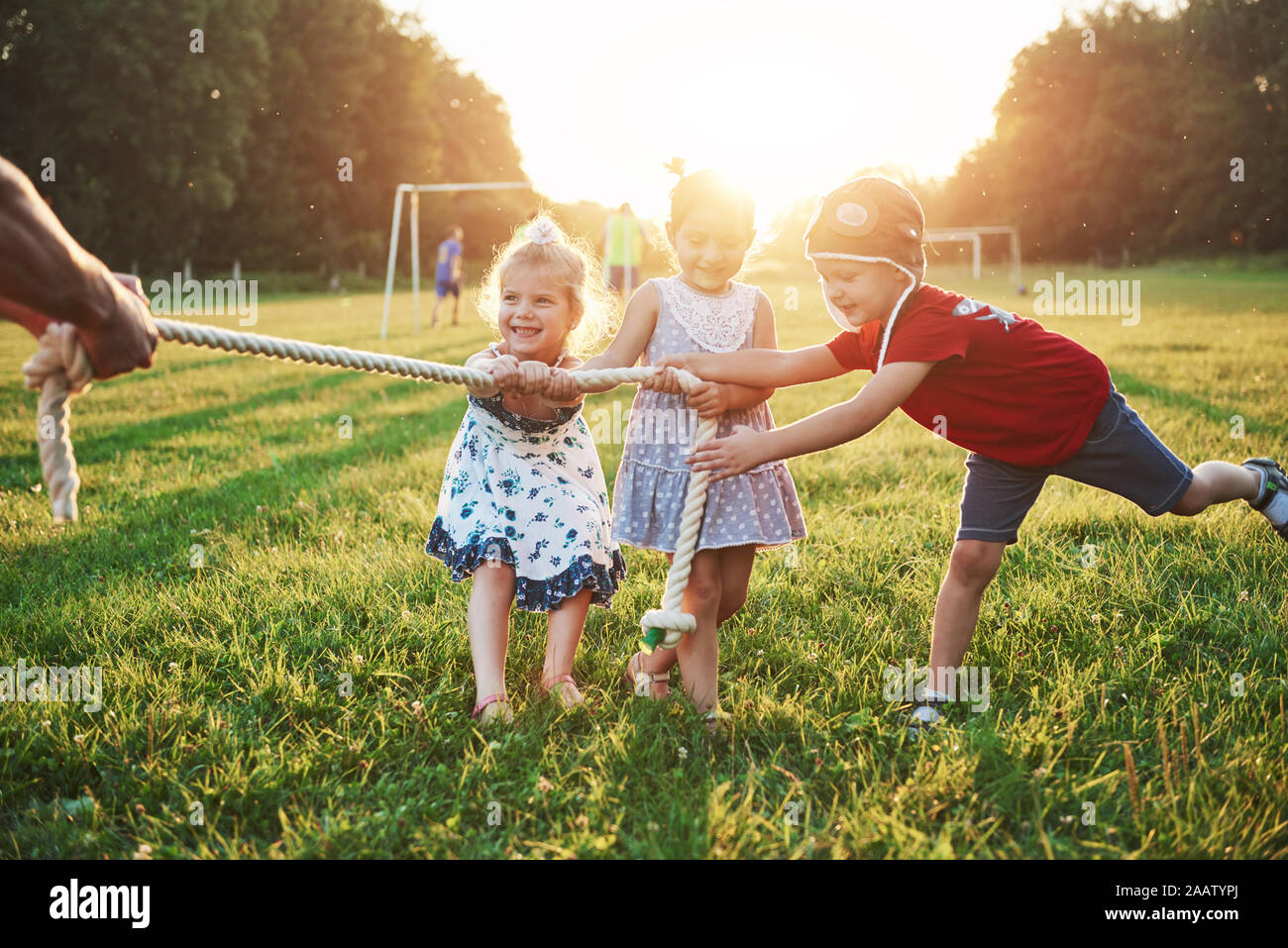 I bambini giocano con il papà nel parco. Non tirare la corda e divertirsi la posa in una giornata di sole Foto Stock