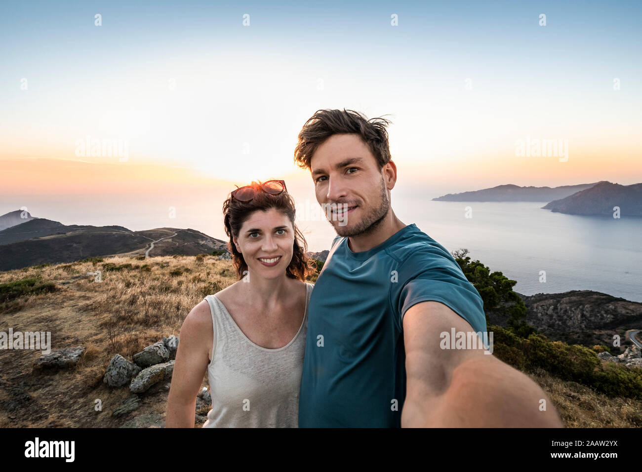 Giovane prendendo un selfie al tramonto, Belvedere de Saliccio, Piana, Corse-du-Sud, Corsica, Francia Foto Stock