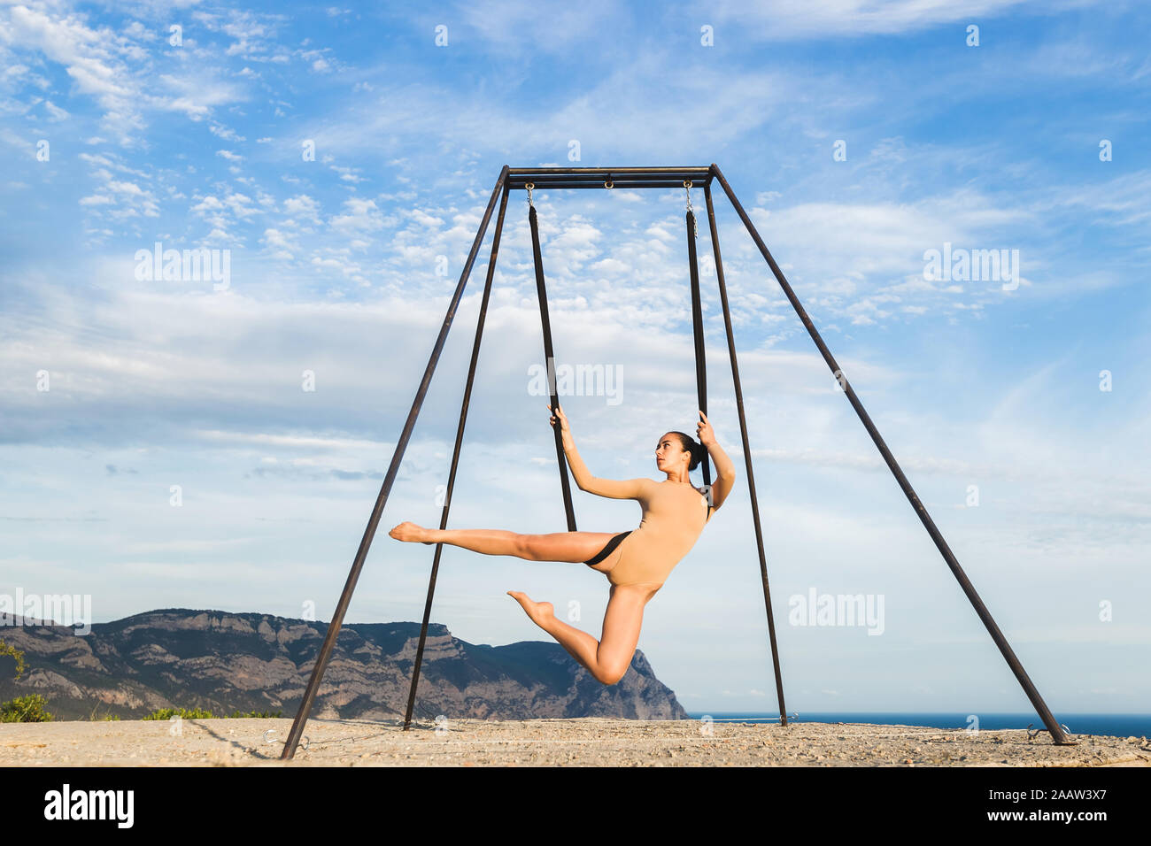 Donna pratica fly dance gravità lo yoga pone in una amaca all'aperto con vista montagna. Uno stile di vita sano, attivo della donna. Foto Stock