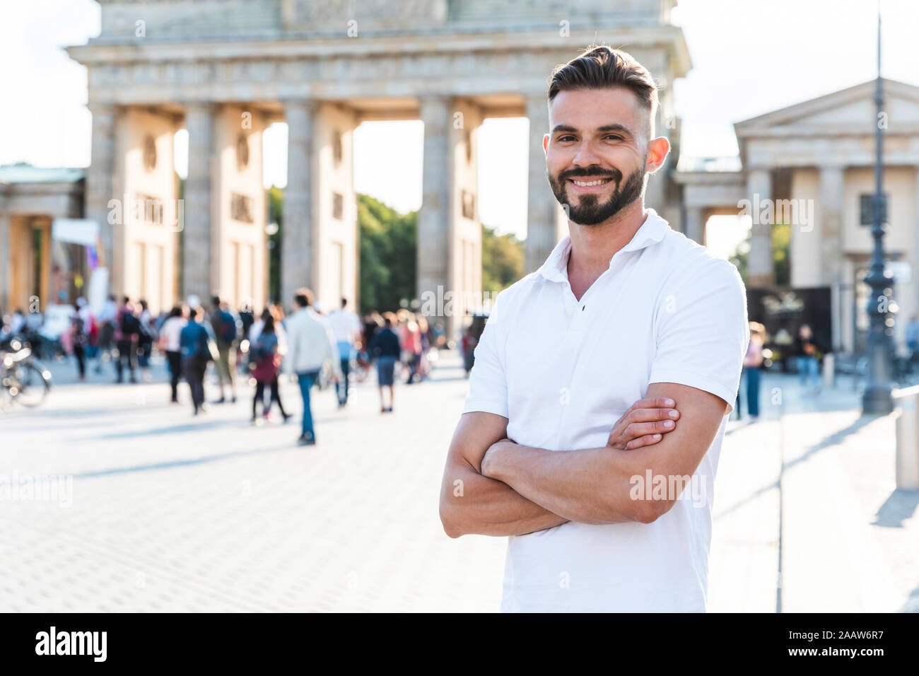 Ritratto di giovane sorridente uomo in piedi nella parte anteriore del Brandenburger Tor, Berlino, Germania Foto Stock