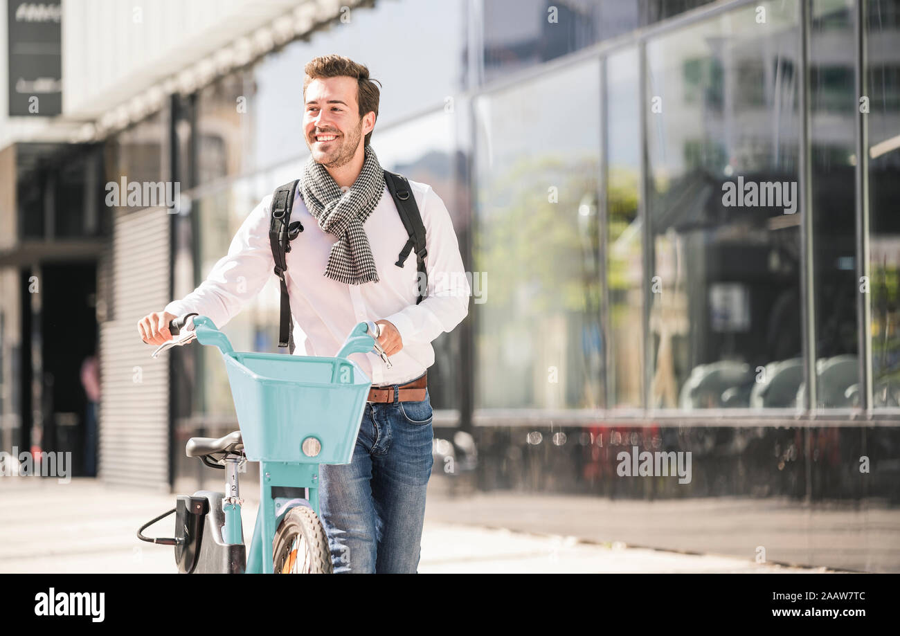 Sorridente giovane con bicicletta in città sul go Foto Stock