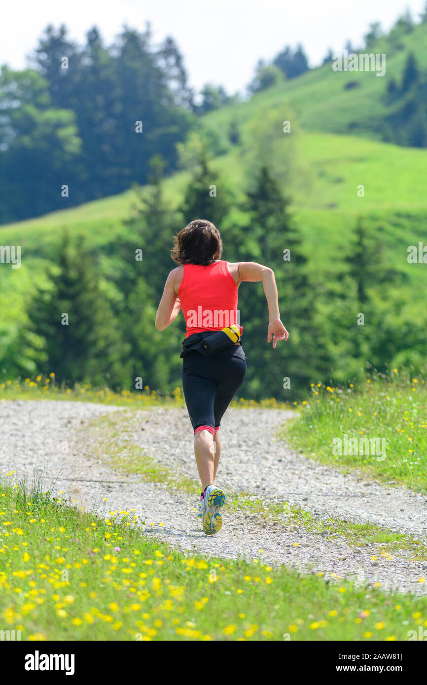 Giovane donna facendo una sessione in esecuzione nel verde della natura alpina Foto Stock