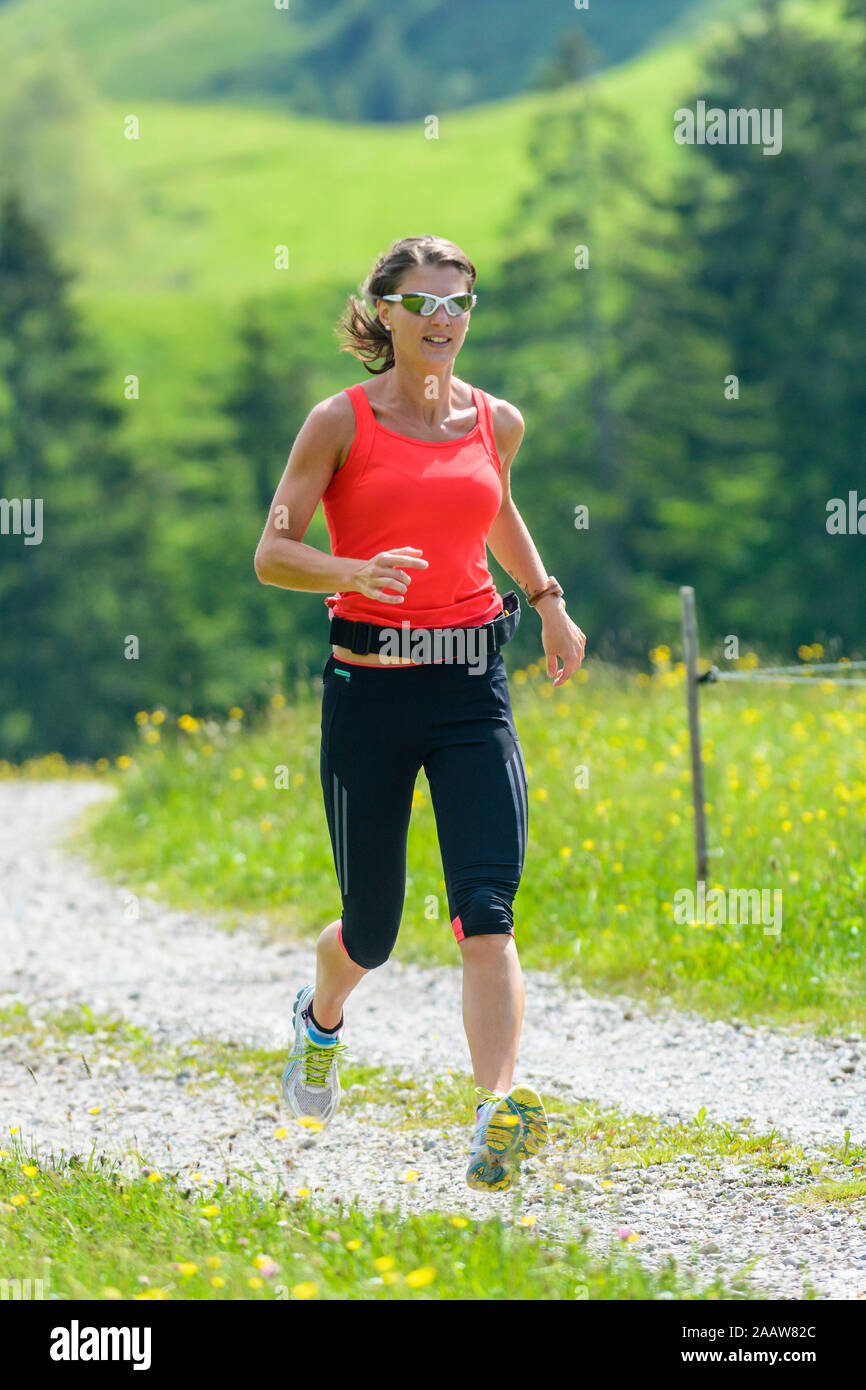 Giovane donna facendo una sessione in esecuzione nel verde della natura alpina Foto Stock