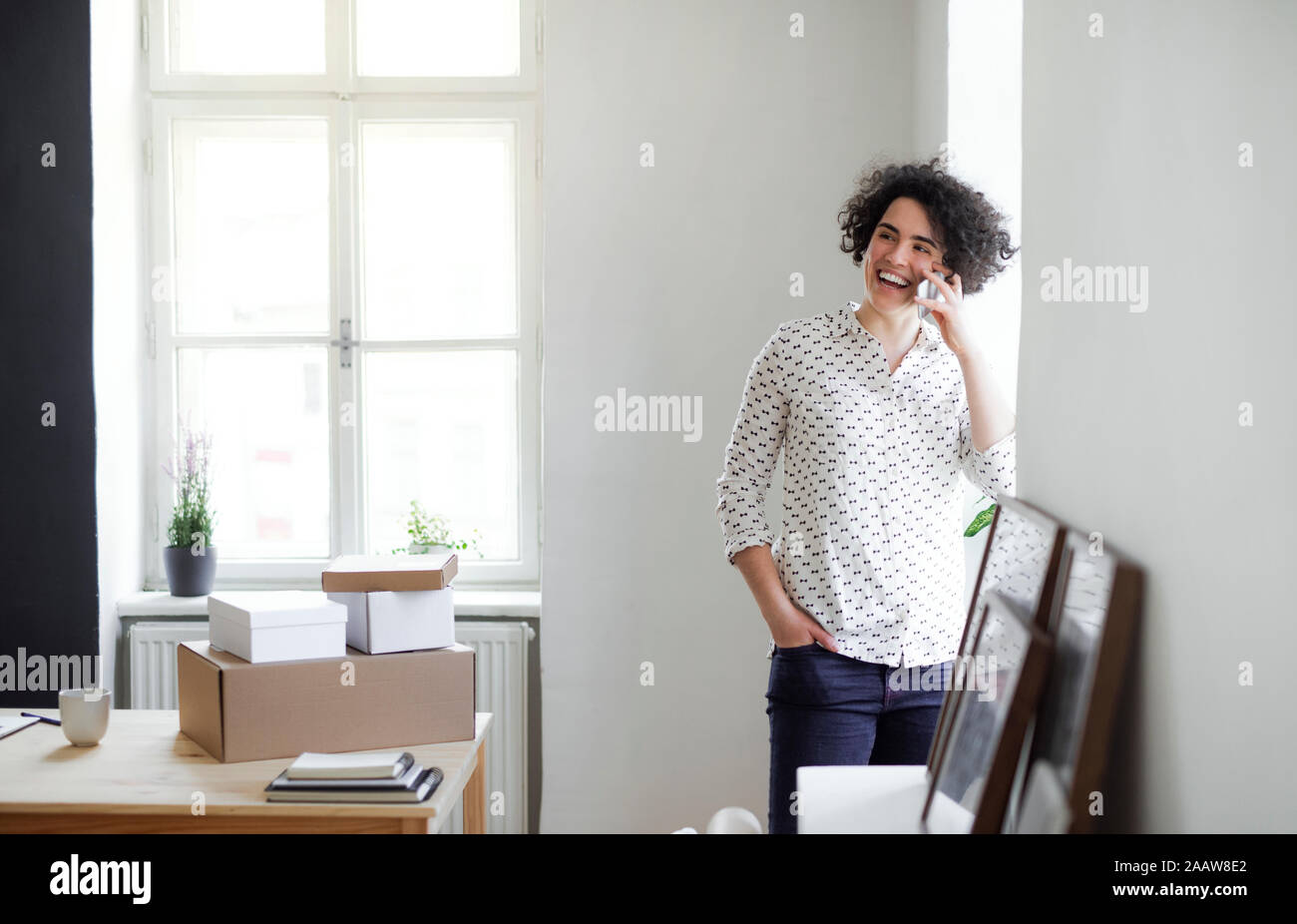 Ridendo giovane donna al telefono in ufficio in casa Foto Stock