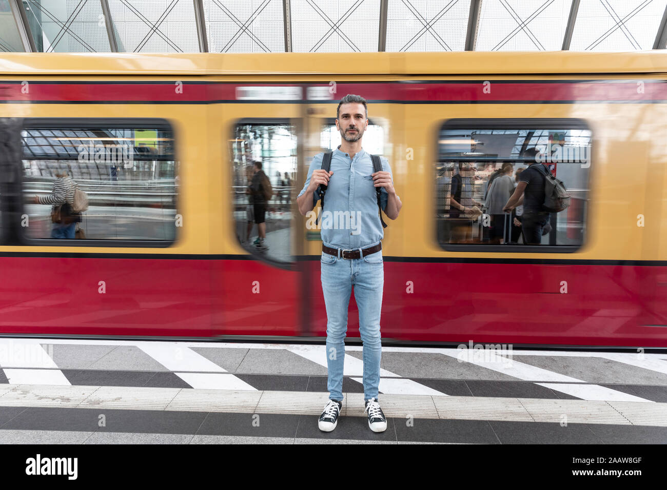 Ritratto dell'uomo alla piattaforma della stazione con treno in background, Berlino, Germania Foto Stock