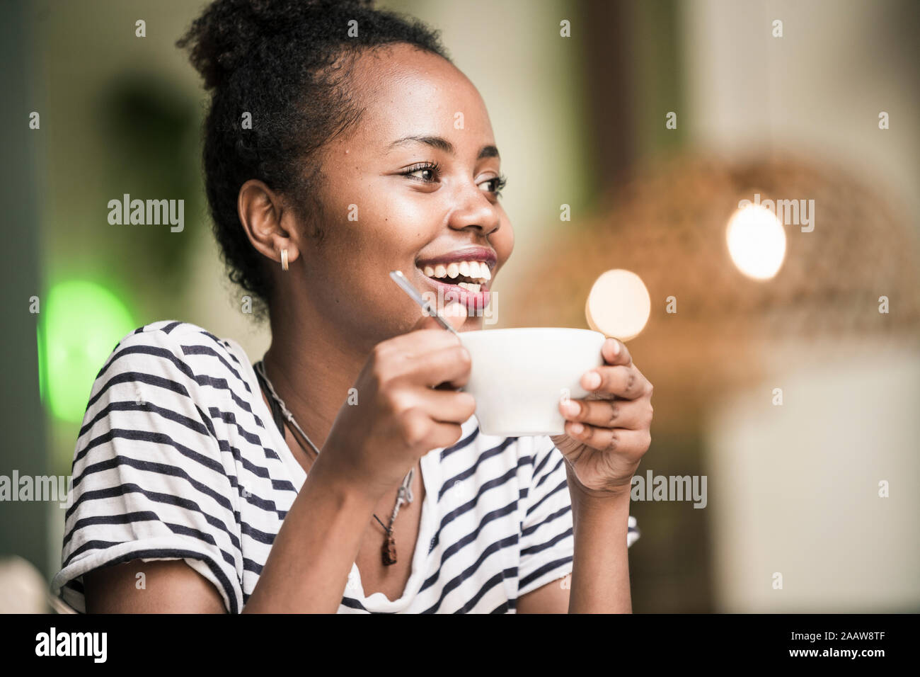 Ritratto di felice giovane donna azienda tazza di caffè in un bar Foto Stock
