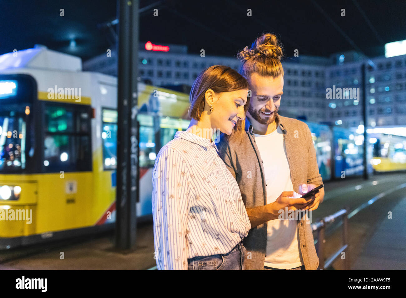 Coppia felice nella città di notte di controllo sui loro telefoni, Berlino, Gernany Foto Stock