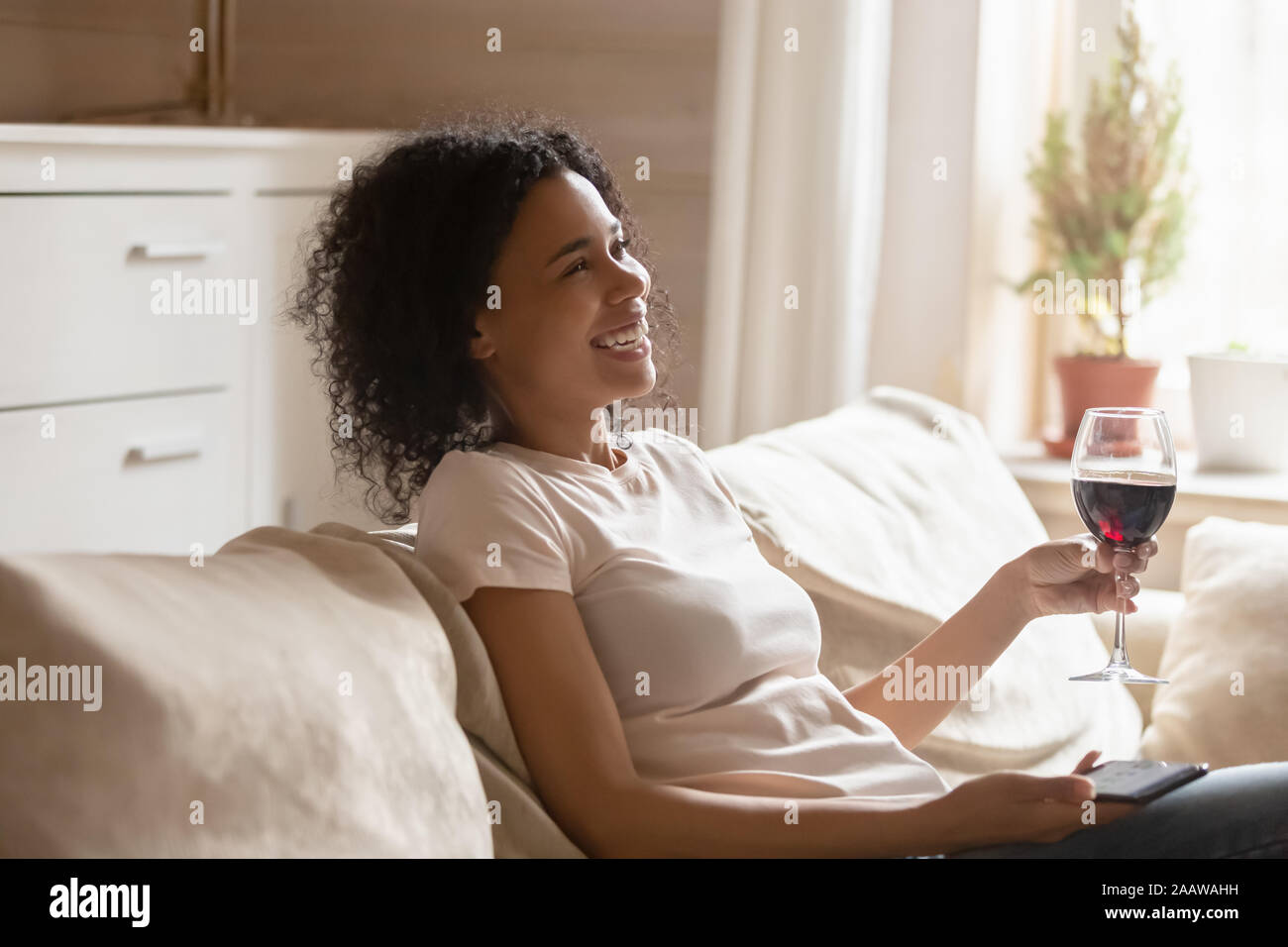 Sorridente americano africano donna rilassarsi su comodi divani Foto Stock