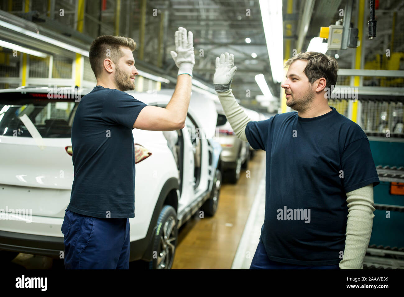 Due colleghi alta fiving nella moderna fabbrica di automobili Foto Stock