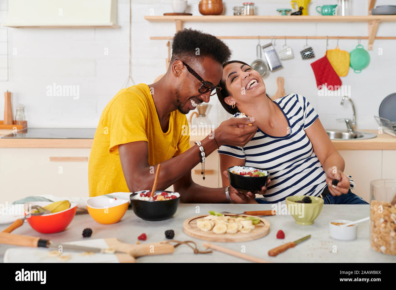 Multietnica giovane ridendo, breakfasting insieme in cucina Foto Stock