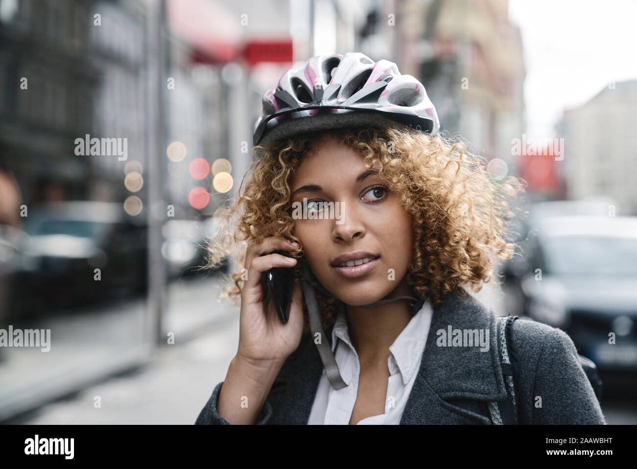 Ritratto di donna con noleggio casco parlando al telefono nella città di Berlino, Germania Foto Stock