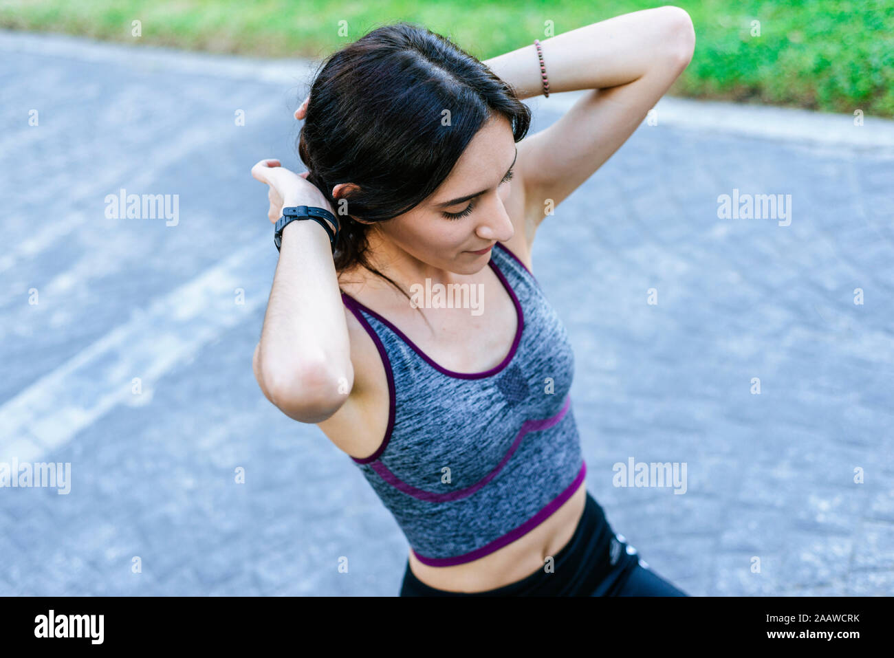 Giovane donna che fissa i suoi capelli mentre si fa sport Foto Stock