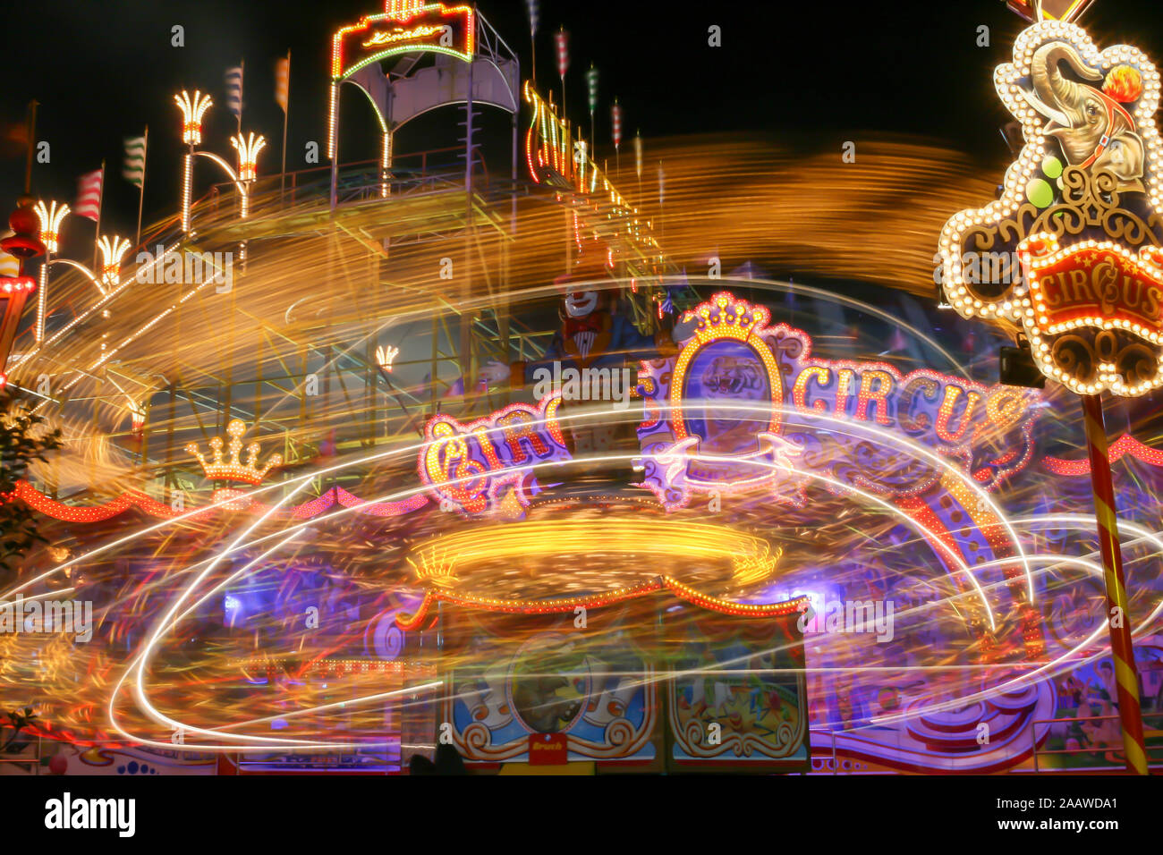 Giostra in movimento. Girato con una lunga esposizione che rappresenta le luci come sentieri di Nizza. Scena al di fuori di un parco di divertimento di notte. Foto Stock