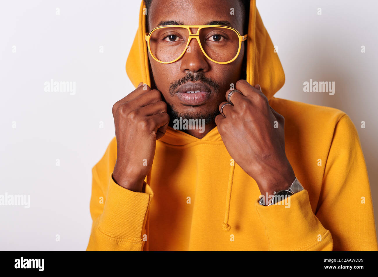 Giovane uomo che indossa giallo felpa hoodie e bicchieri Foto Stock