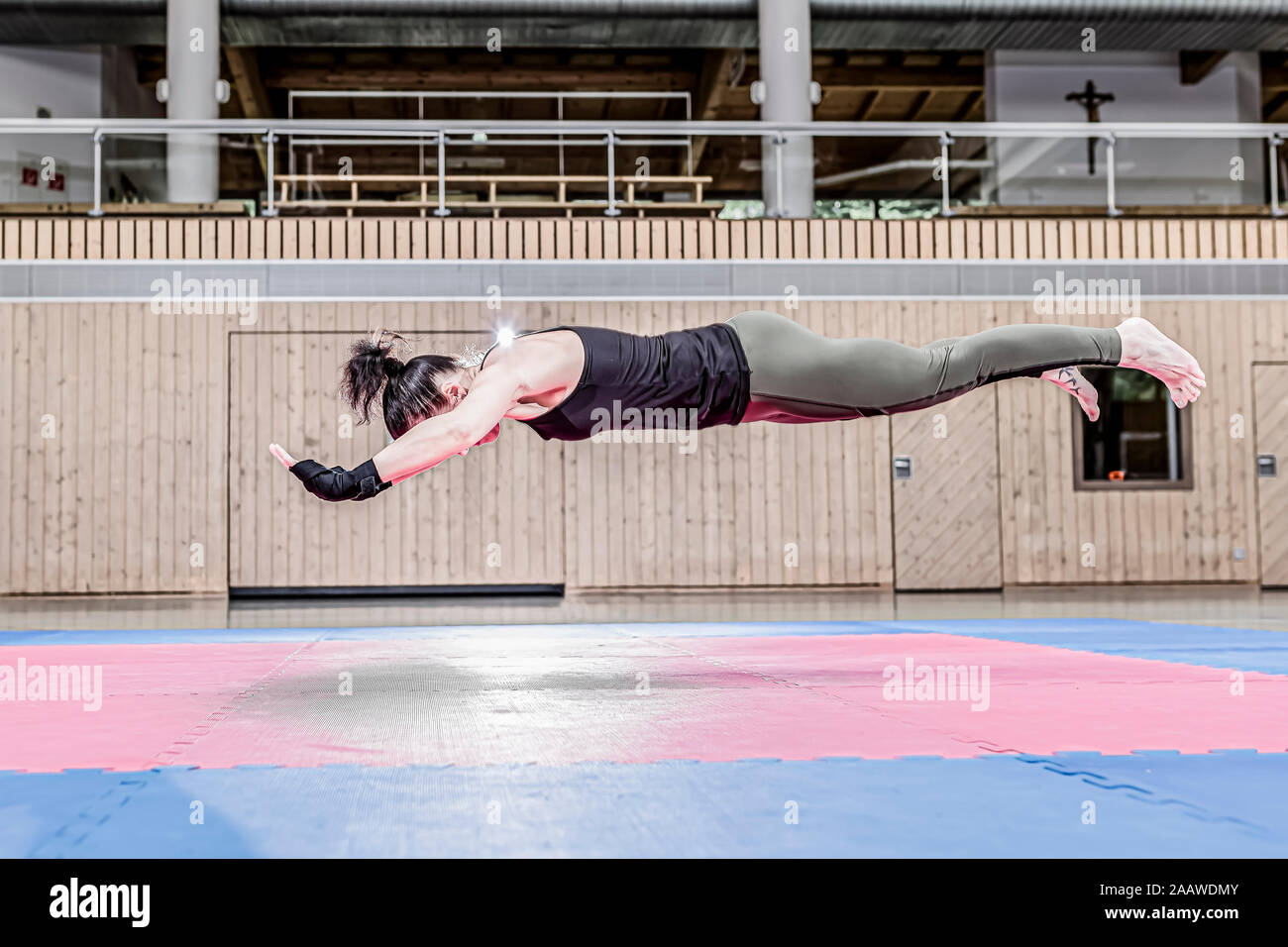 Donna di esercitare nella sports hall floating mid-air Foto Stock