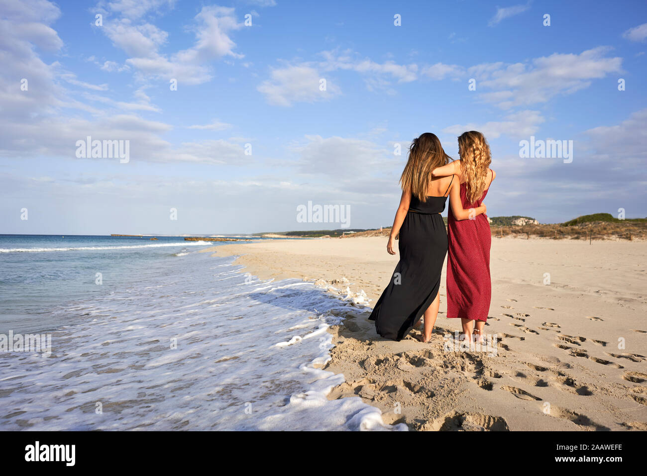 Due giovani donne in piedi sotto braccio su una spiaggia Foto Stock