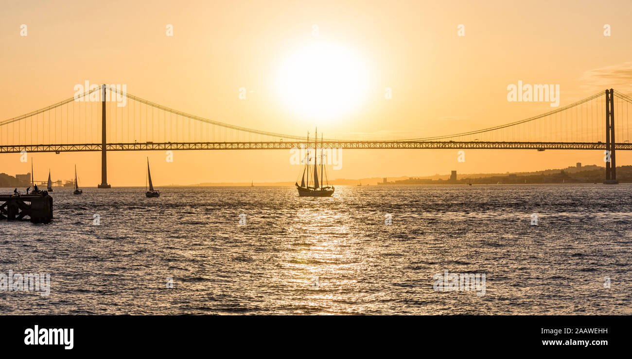Xxv Aprile ponte sul fiume Tago contro il cielo arancione a Lisbona, Portogallo Foto Stock