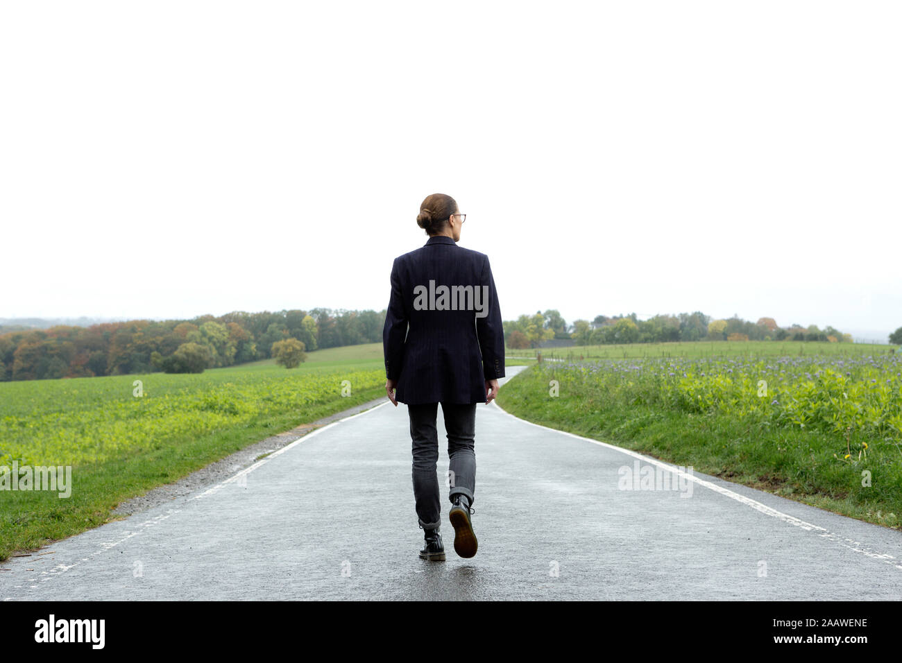 Vista posteriore di una donna senior facendo una passeggiata sulla strada di un paese Foto Stock