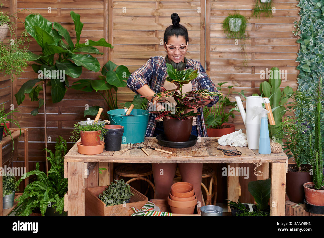 Sorridente giovane donna giardinaggio sul suo terrazzo Foto Stock