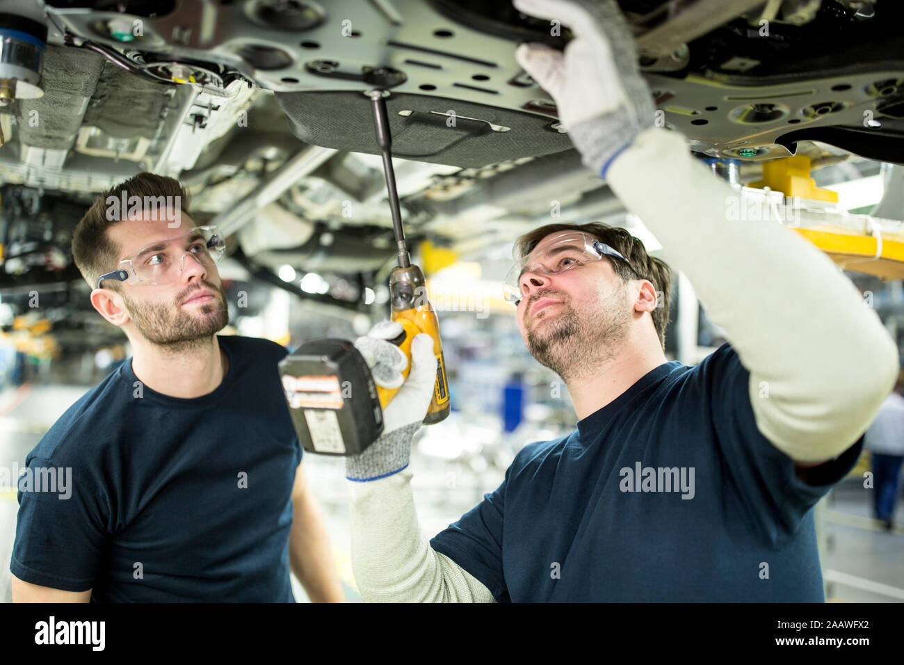 Due colleghi di lavoro auto al sottocarro in fabbrica moderna Foto Stock
