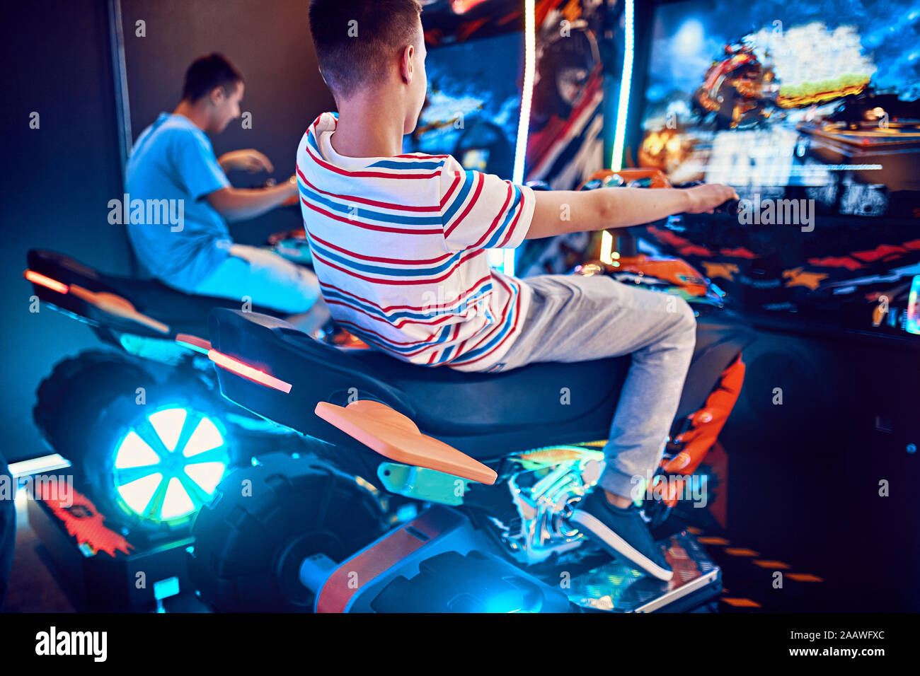 Teenage amici a giocare con un simulatore di guida in una sala giochi Foto Stock