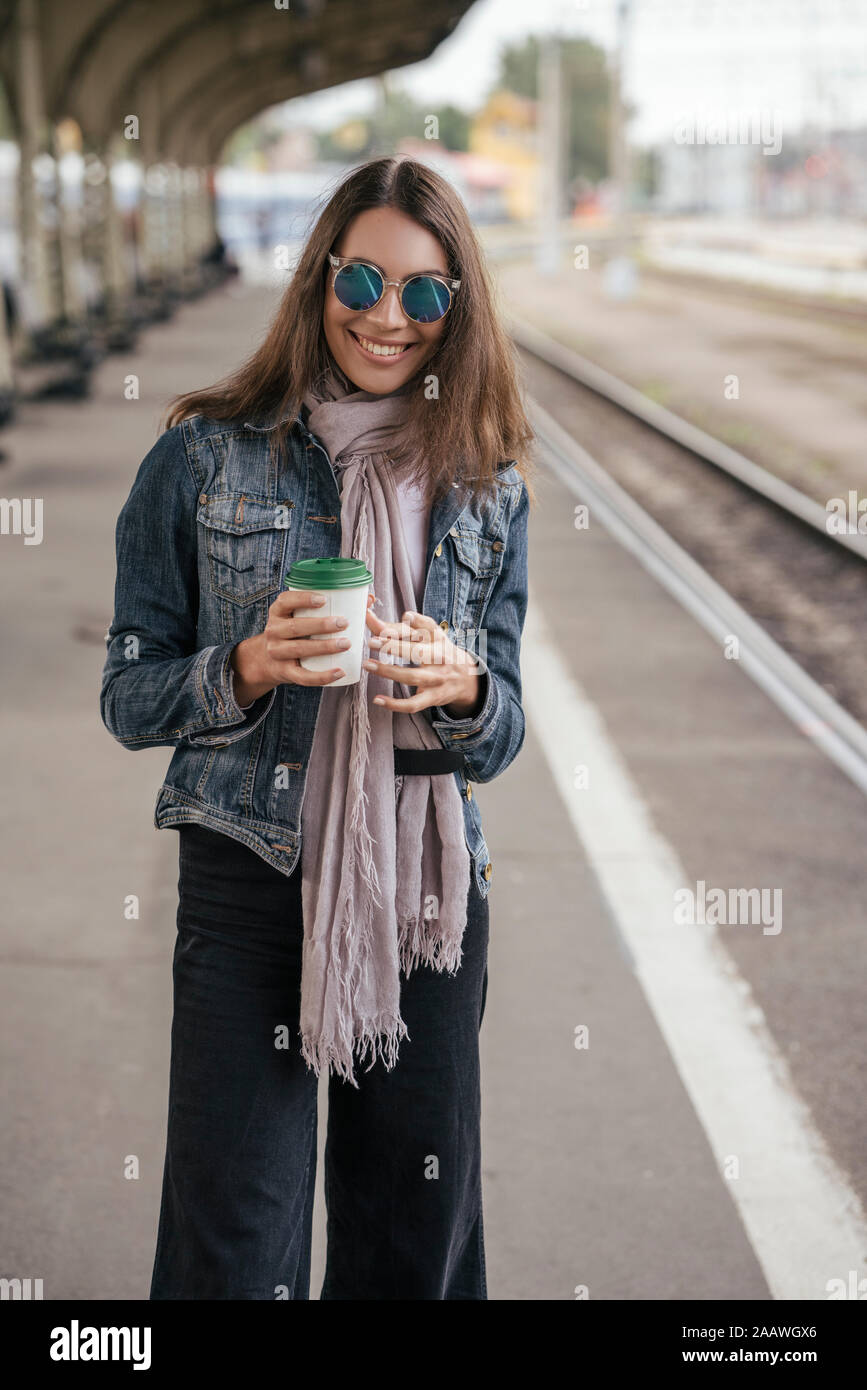 Giovani viaggiatori sorridente con caffè per andare sulla stazione ferroviaria Foto Stock