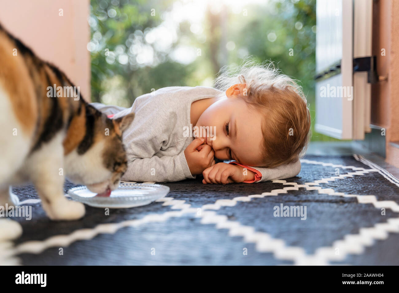 Carino il toddler girl watching cat di bere dalla ciotola Foto Stock