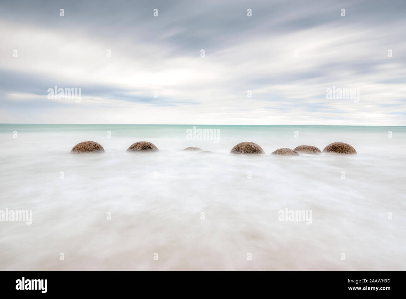 Moeraki Boulders in mare in spiaggia Koekohe contro il cielo nuvoloso durante il tramonto, Nuova Zelanda Foto Stock