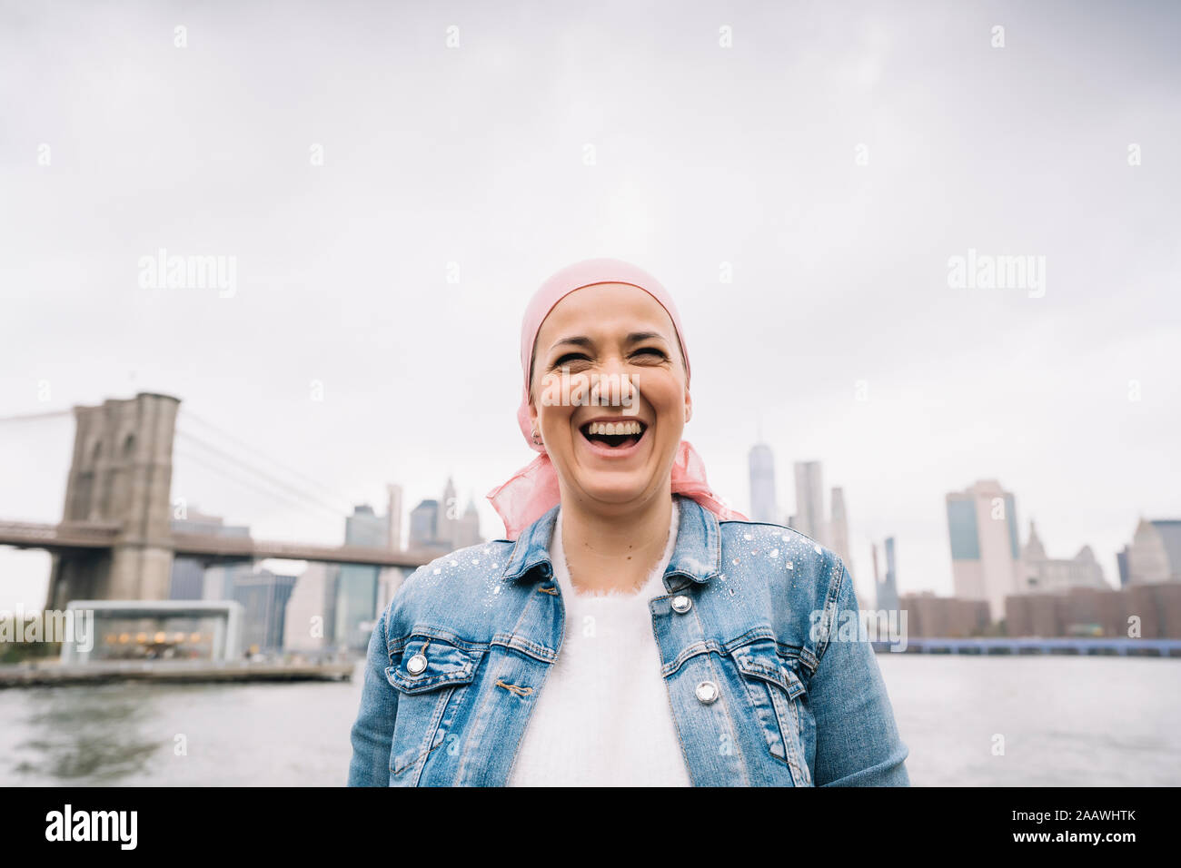 Ritratto di donna ridere con cancro bandana al Ponte di Brooklyn a New York, Stati Uniti d'America Foto Stock