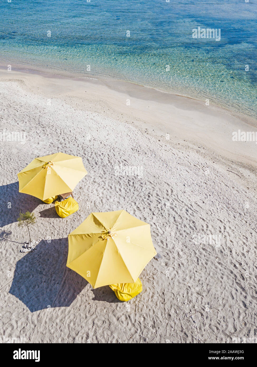 Drone shot di giallo ombrelloni in spiaggia durante il giorno soleggiato, Gili-Air Isola, Indonesia Foto Stock