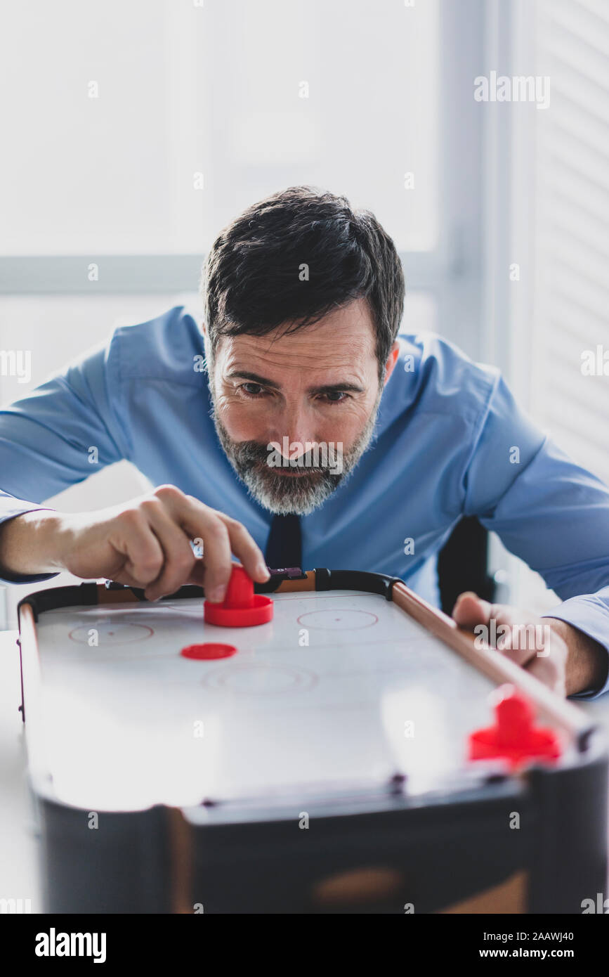 Imprenditore maturo giocare air hockey Foto Stock