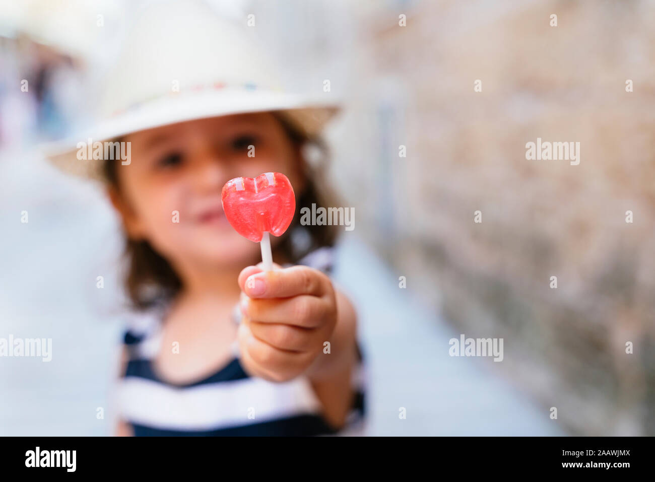 Poco la mano della bambina tenendo a forma di cuore lecca-lecca, close-up Foto Stock