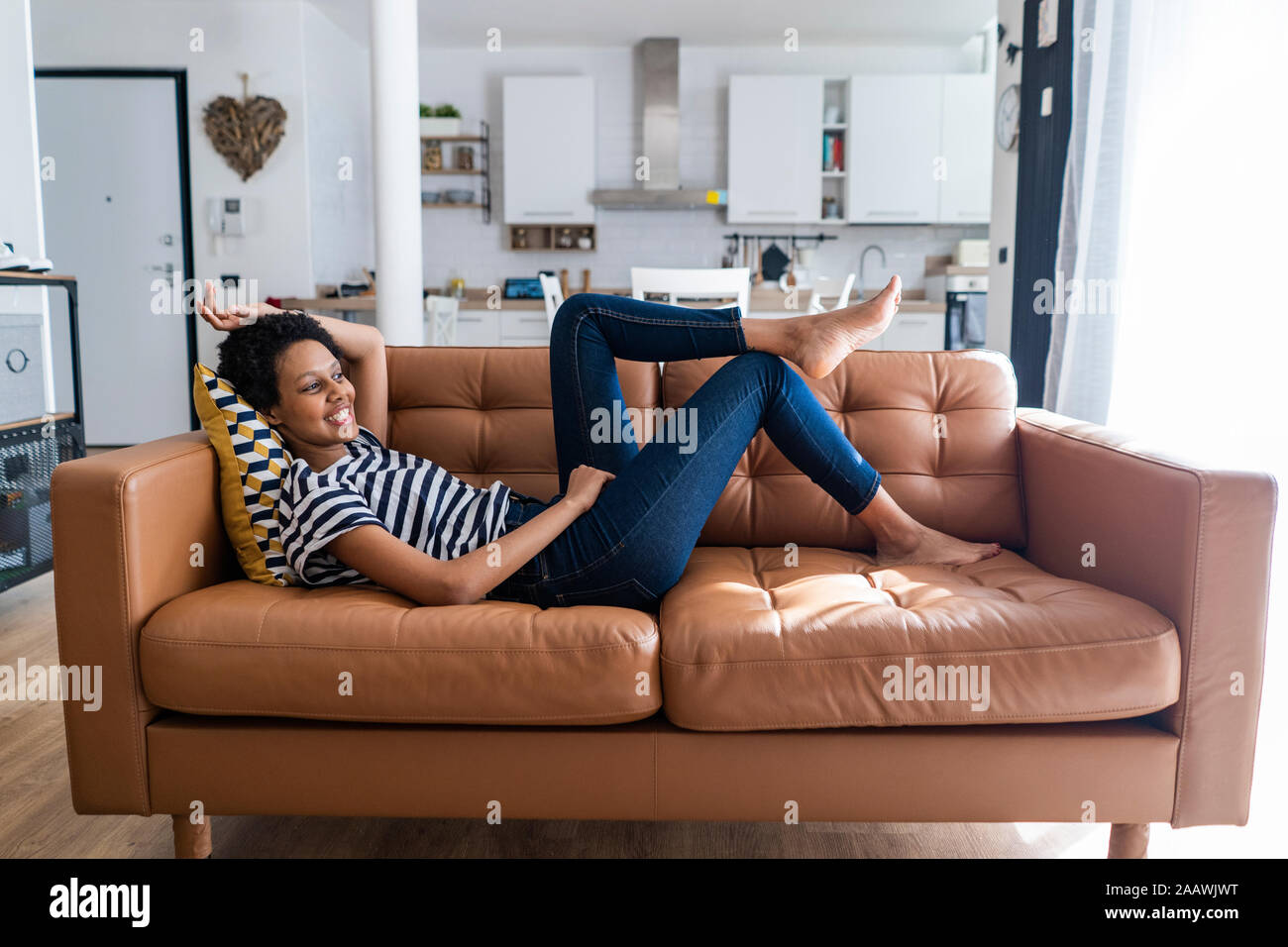 Rilassata giovane donna sdraiata sul divano di casa Foto Stock