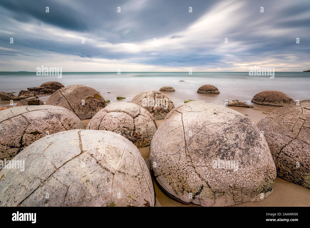 Moeraki Boulders on shore contro il cielo nuvoloso a Koekohe Beach, Isola del Sud, Nuova Zelanda Foto Stock