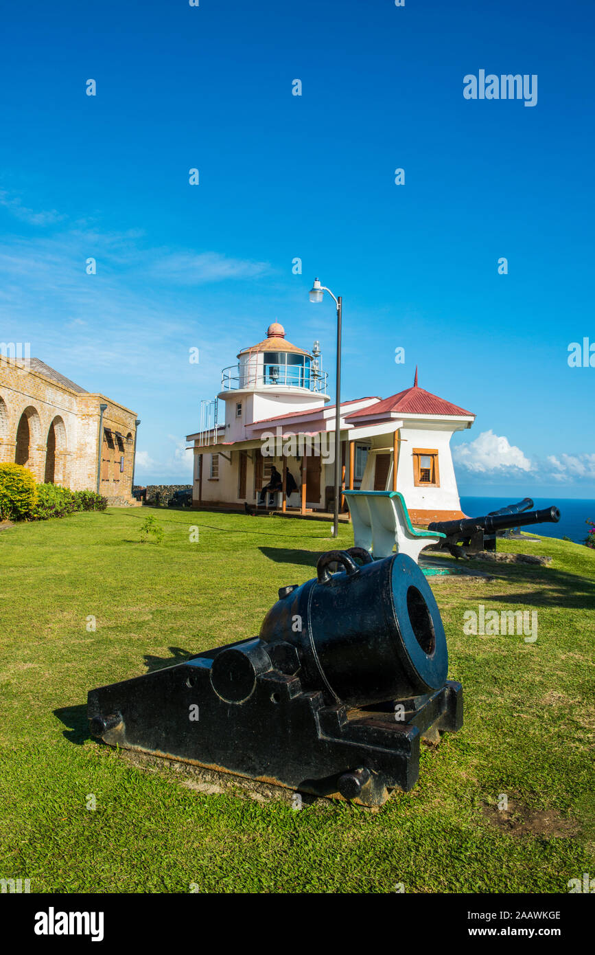 Vista del cannone in terra con Fort King George in background contro il cielo blu, a Scarborough, Trinidad e Tobago, dei Caraibi Foto Stock